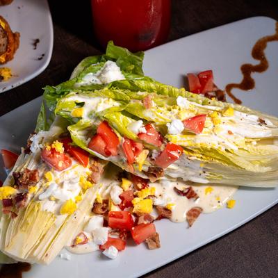 Wedge salad with tomatoes, bacon, egg, and creamy dressing.