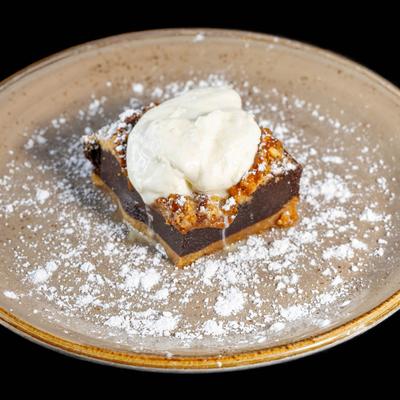 Salted caramel pretzel brownie with whipped cream and powdered sugar.