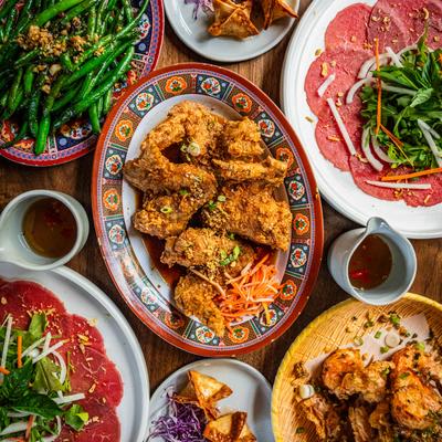 Assortment of food dishes spread on a wooden table, top down view.
