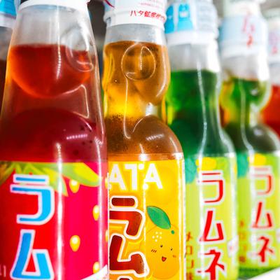 Close-up of colorful Japanese soda bottles lined up on a fridge shelf.