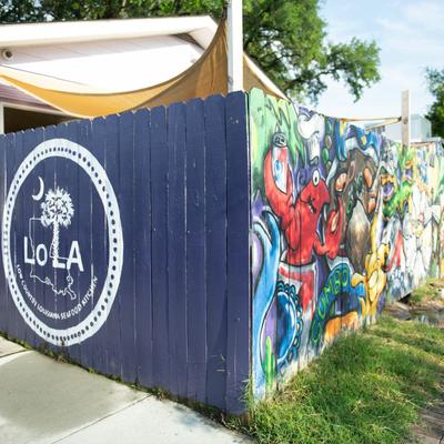 Exterior, restaurant's logo and graffiti on a fence.