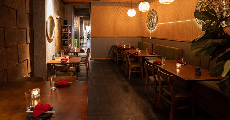 A warmly lit interior with wooden decor and tables set for dining