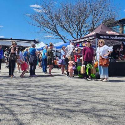 A group of customers waiting  in line in front of Rosita's Cocina food stand.