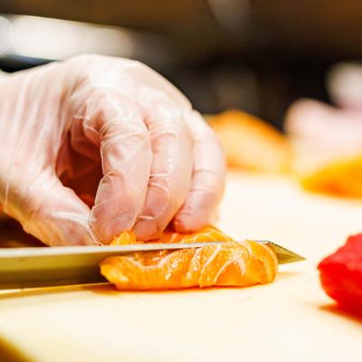 Chef carefully slices fresh salmon on a cutting board.