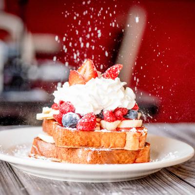 Stuffed French Toast being dusted with powdered sugar.