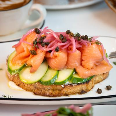 Smoked salmon toast topped with cucumber slices, pickled onions, and capers.