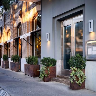 Restaurant entrance featuring metal planters and wall-mounted menu box.