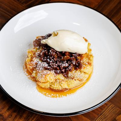 Maple bourbon bread pudding topped with cream, toasted pecans, and powdered sugar.