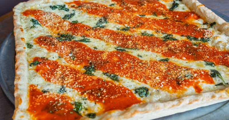 Rectangular pizza topped with tomato sauce, cheese and herbs