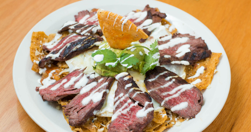 Steak and fried corn tortillas served on a plate