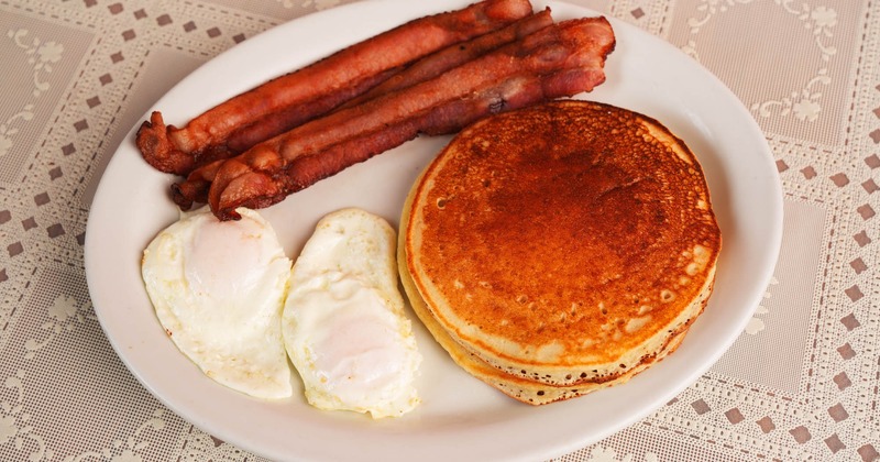 Two fried eggs with pancakes and crispy bacon