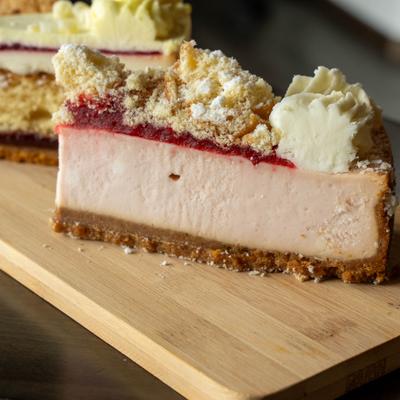 Cheesecake slice served on a wooden tray alongside other desserts, closse-up.