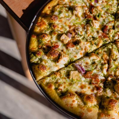 Pesto pie with cheese, grilled chicken, onion mix, garlic and bacon.
