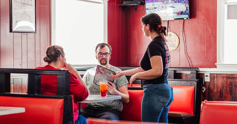 Employee handing customers a menu