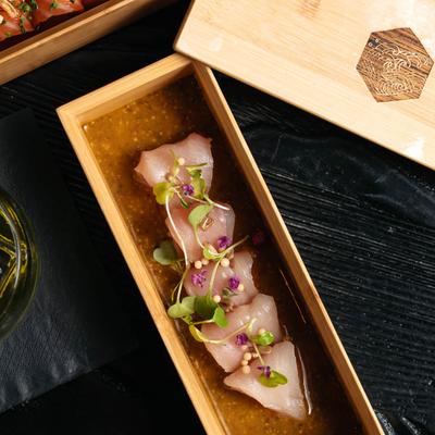 Yellowtail fish sashimi topped with microgreens and edible flowers.