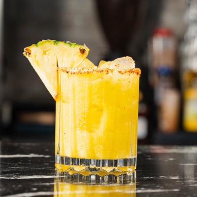 The Avocado cocktail, tajin rim, garnished with pineapple wedge.