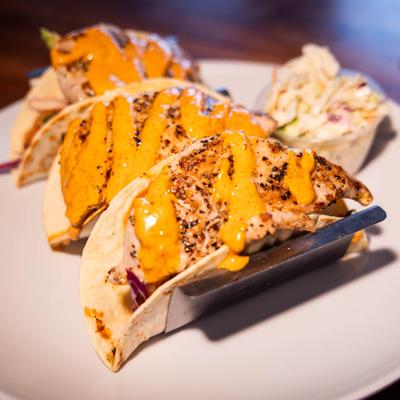 Three chicken tacos, served with a side of coleslaw, front view.