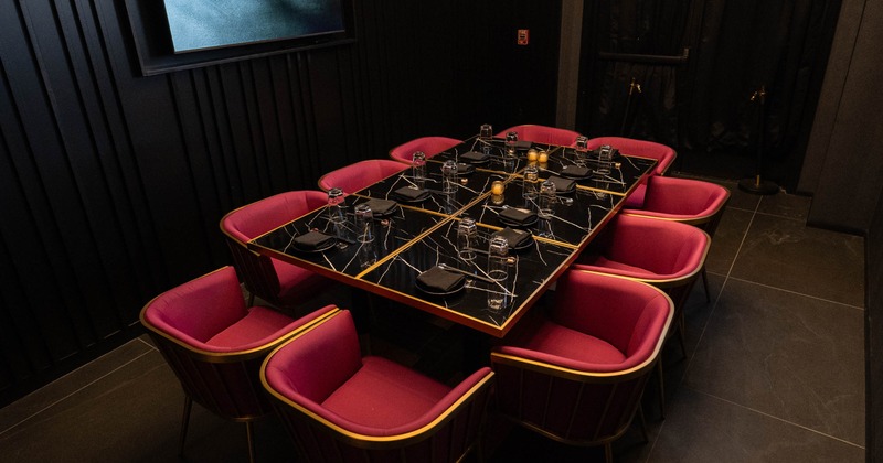 Private dining room with long table set for dining and red chairs