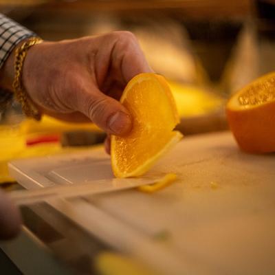 Person slicing a fresh orange on a cutting board.