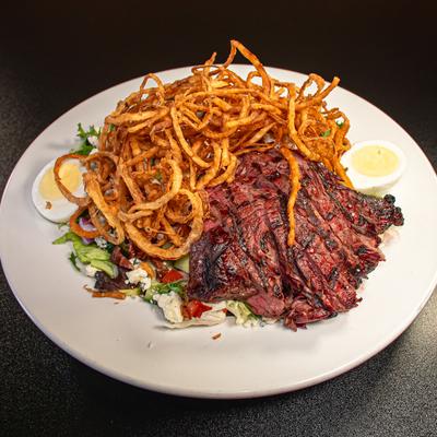 Cobb salad with grilled steak, hard-boiled egg and crispy onion strings.