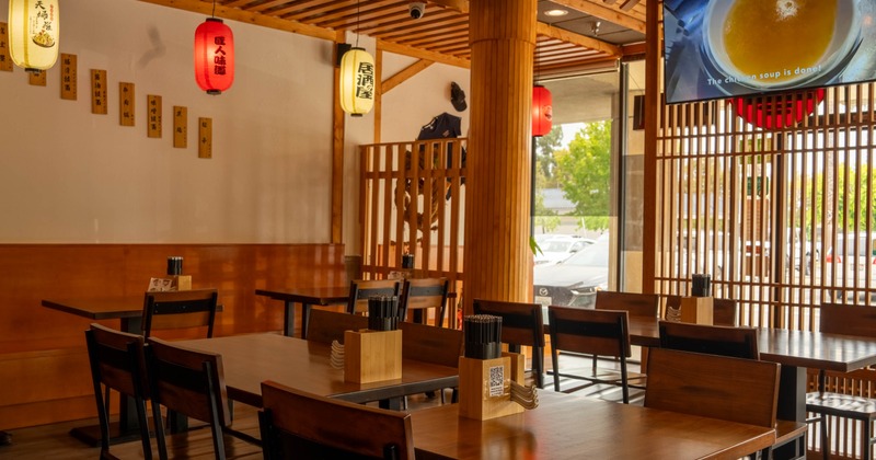 Interior of a Japanese-style restaurant with wooden decor, lattice panels and hanging lanterns