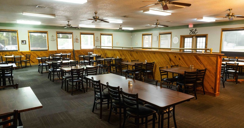 Restaurant interior with wooden tables, chairs, and decorative wall panels