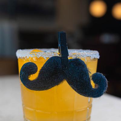 Margarita cocktail with decorative mustache attached to the glass.