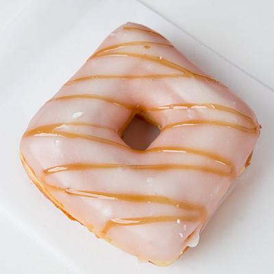 A glazed pink square donut drizzled with caramel.