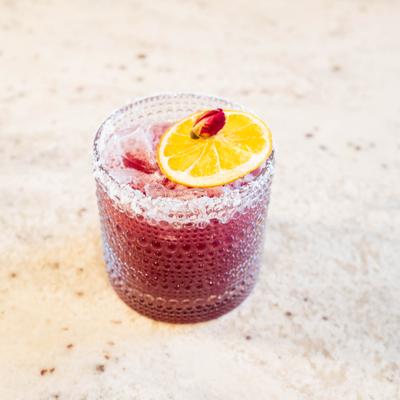 Blueberry Margarita garnished with orange wheel and dried rose petal.