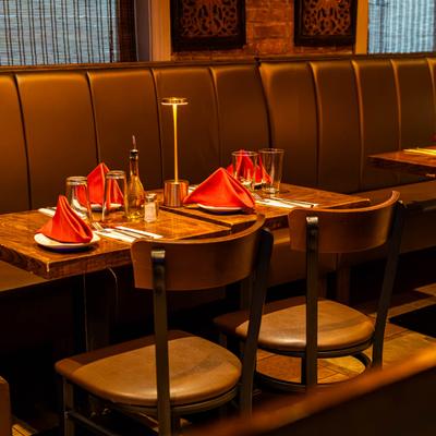 Interior, a banquette seating with tables set for dining and wooden chairs.