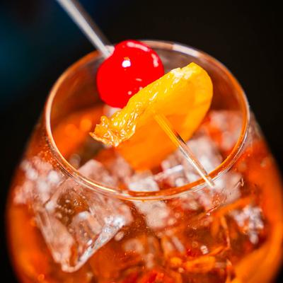 Orange Brandy Old Fashioned, garnished with cherry and orange slice, close up.