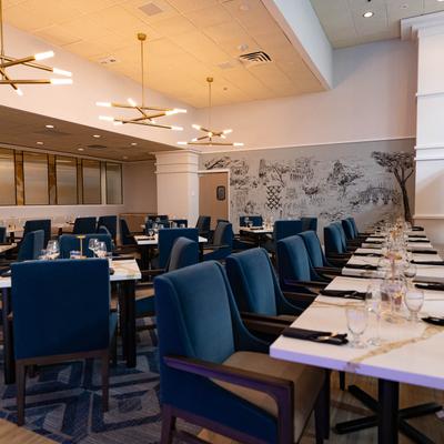 Elegant dining room with blue upholstered chairs and white marble-top tables.