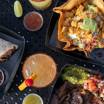 Aerial table view of margarita, tostada supreme, salsa and carne asada plate.