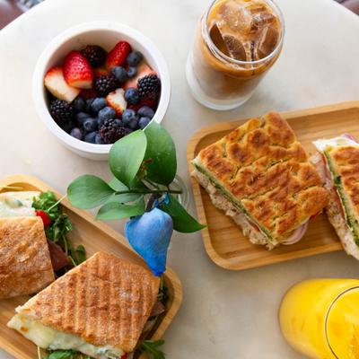 Grilled sandwiches with iced coffee and a fruit bowl.