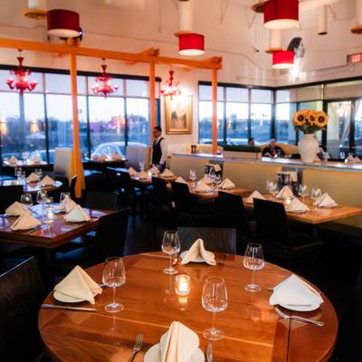 Elegant restaurant dining room with set tables and large windows.