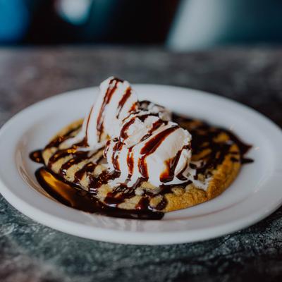 A chocolate chip cookie topped with ice cream and chocolate sauce.