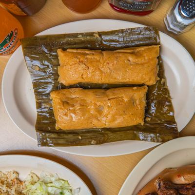 Tamales served on a banana leaf on a plate.