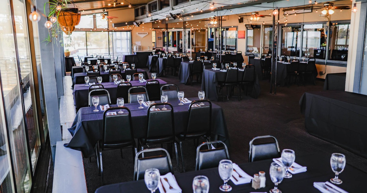 Spacious banquet hall with black tablecloths, neatly set with glassware and white napkin