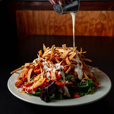 Buffalo Chicken Salad, with spring mix, tomato, onion, peppers, cheese, and tortilla strips.