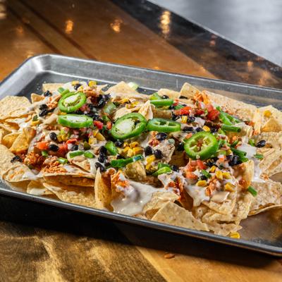 Loaded nachos topped with corn, black beans, cheese sauce, and jalapenos.