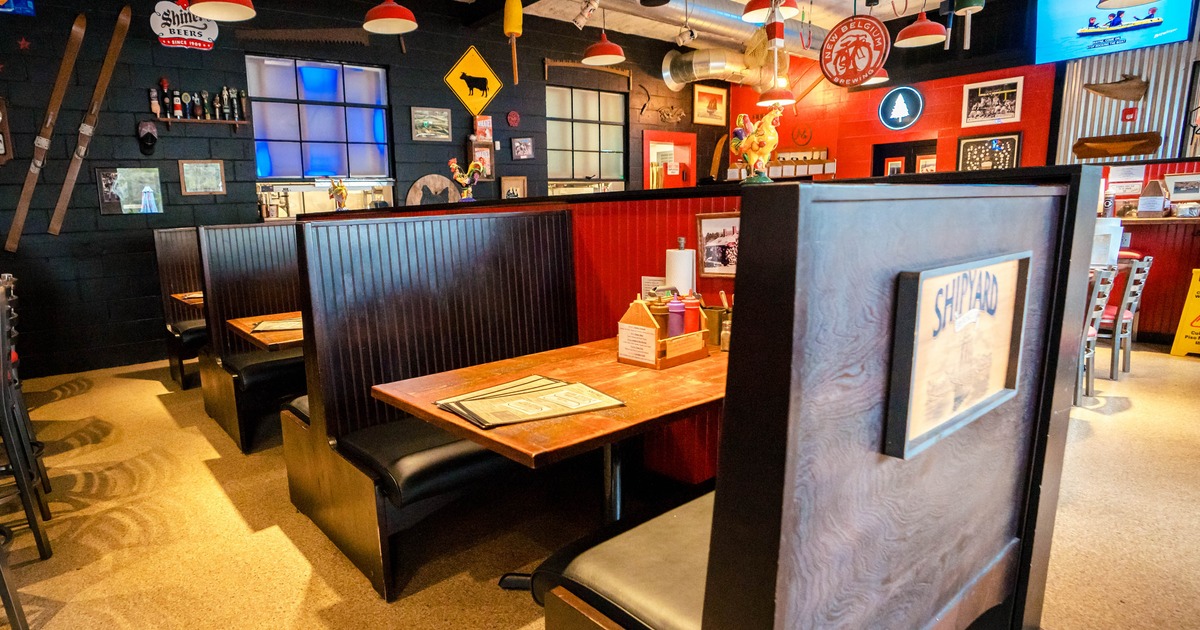 Interior of a restaurant with wooden booths, colorful decor, and pendant lights