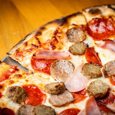 Close up of a pizza with tomato sauce, mozzarella and meats.