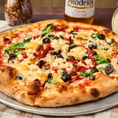 Greek Pie topped with black olives, sun-dried tomatoes, artichokes, and spinach.