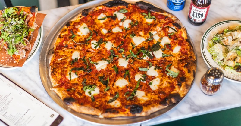 Margherita pizza,  slice of Prosciutto and Arugula pizza, Caesar salad