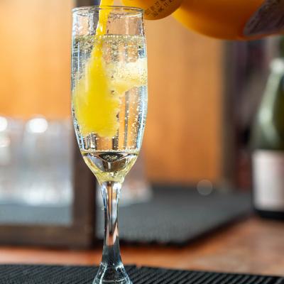A glass of champagne being topped with orange juice.
