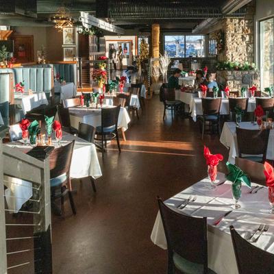 Cozy restaurant with white tablecloths and red and green folded napkins, warm ambiance.