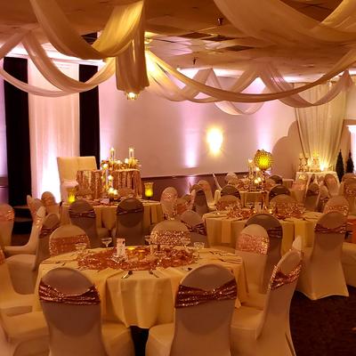 Elegant banquet hall with draped ceiling decorations and soft ambient lighting.