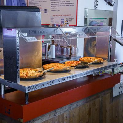 Glass pizza display marked with Caution Hot.