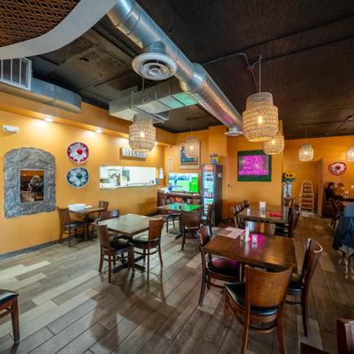 Interior with wooden tables, yellow walls, and woven pendant lights.