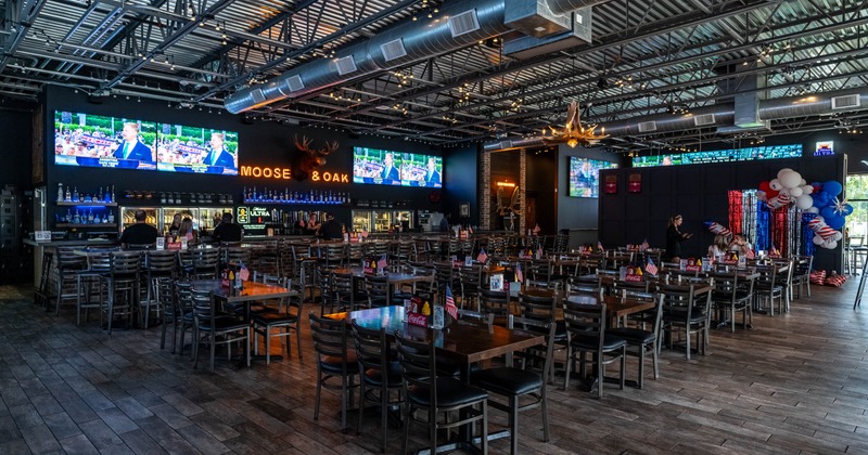 Interior, wooden tables, a bar with illuminated shelves, and TVs broadcasting news